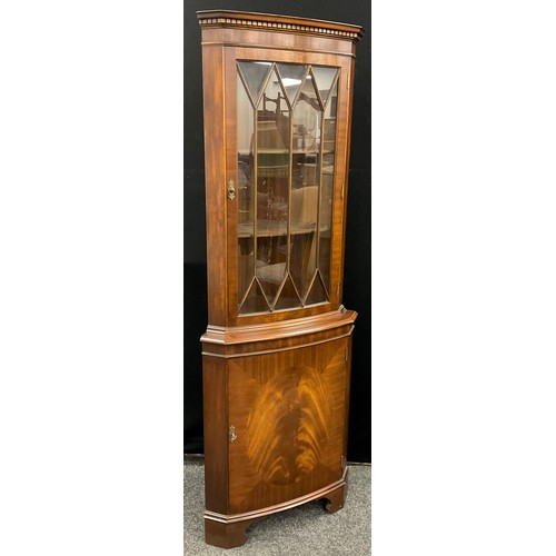 173 - A reproduction Georgian style corner cabinet, dentil cornice, astral-glazed top door enclosing two t... 