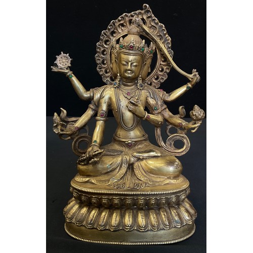 230A - A Tibetan gilt bronze coloured metal Buddhistic figure, Bodhisattva seated, her six arms each holdin... 