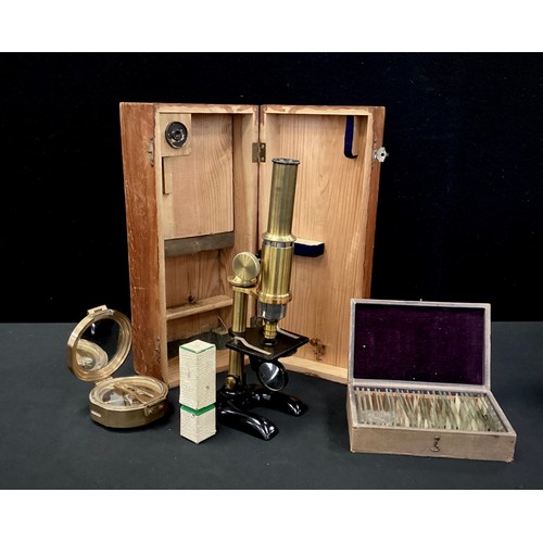 213 - An early 20th century monocular microscope, with pine case;  a box of approximately 25 prepared slid... 