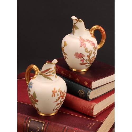 121 - A pair Royal Worcester flat back jugs, decorated in the Aesthetic manner with floral sprays in muted... 