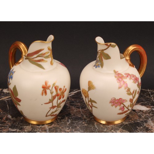 121 - A pair Royal Worcester flat back jugs, decorated in the Aesthetic manner with floral sprays in muted... 