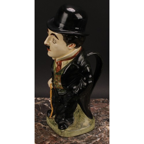 27 - A Royal Doulton jug and cover, modelled as Charlie Chaplin, he stands wearing baggy black suit with ... 