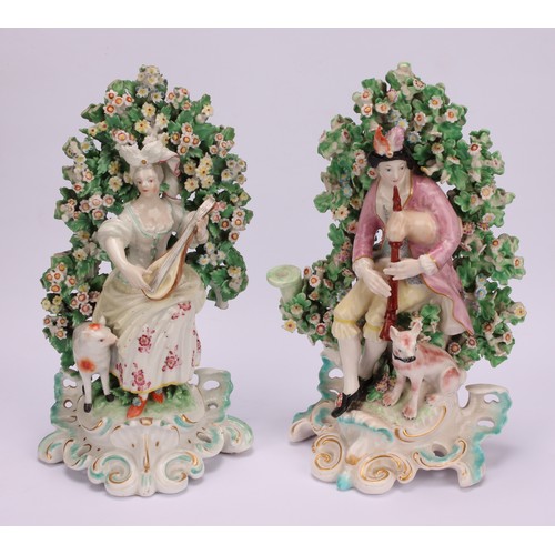 185 - A pair of Derby Patch Mark figures, of a shepherd and shepherdess, he seated wearing feathered headd... 