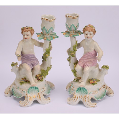 181 - A pair of Continental porcelain figural candlesticks, probably Samson, modelled with seated putto, e... 