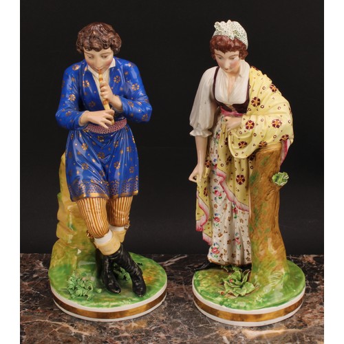 180 - A pair of Bloor Derby figures, of a musician and his companion, he seated on rocky outcrop playing h... 