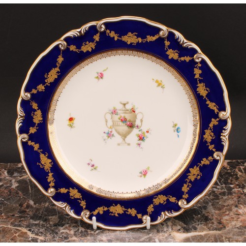 234 - A set of six Royal Crown Derby shaped circular plates, each decorated with a pedestal urn draped in ... 