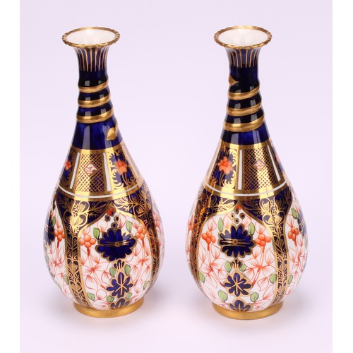 196 - A pair of Royal Crown Derby 1128 Imari pattern ovoid bottle vases, the slender necks moulded with sp... 