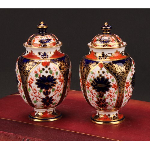 197 - A pair of Royal Crown Derby 1128 Imari pattern ovoid pedestal vases and covers, circular bases, 13cm... 