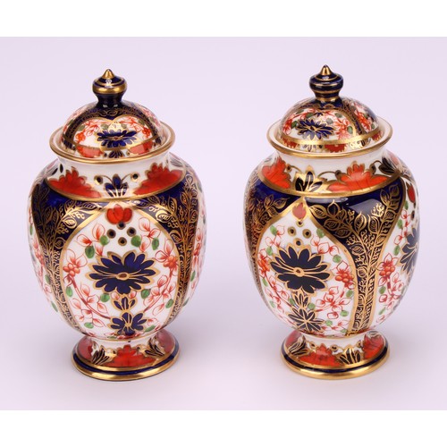 197 - A pair of Royal Crown Derby 1128 Imari pattern ovoid pedestal vases and covers, circular bases, 13cm... 