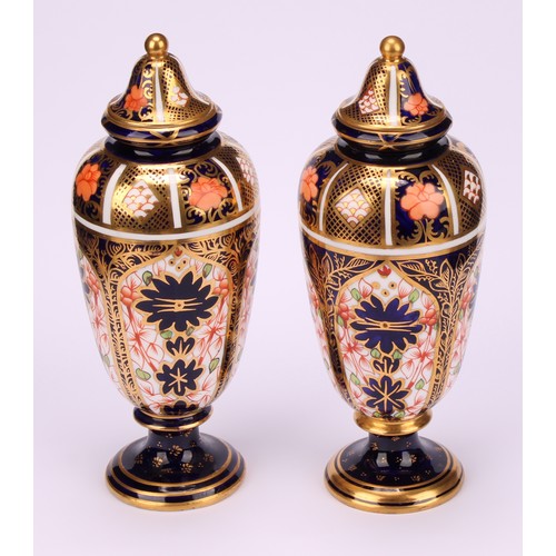 199 - A pair of Royal Crown Derby 1128 Imari pattern slender ovoid pedestal vases, domed covers, gilt ball... 