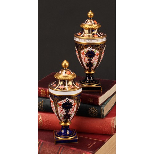 194 - A near pair of Royal Crown Derby 1128 Imari pattern ovoid pedestal vases, domed covers, gilt finials... 