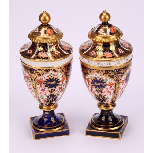 194 - A near pair of Royal Crown Derby 1128 Imari pattern ovoid pedestal vases, domed covers, gilt finials... 