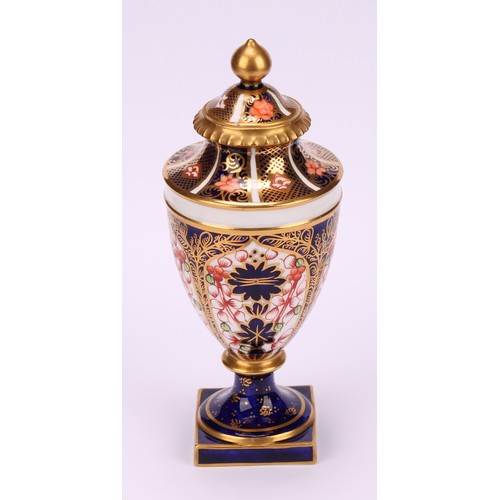 194 - A near pair of Royal Crown Derby 1128 Imari pattern ovoid pedestal vases, domed covers, gilt finials... 