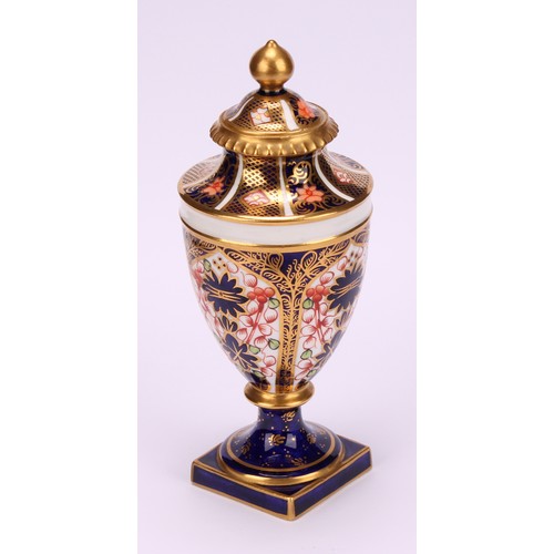 194 - A near pair of Royal Crown Derby 1128 Imari pattern ovoid pedestal vases, domed covers, gilt finials... 