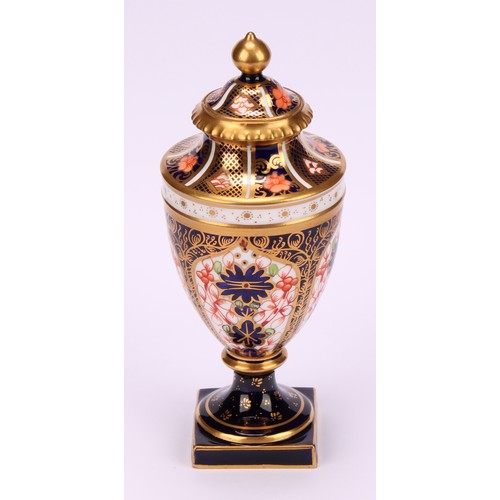 194 - A near pair of Royal Crown Derby 1128 Imari pattern ovoid pedestal vases, domed covers, gilt finials... 