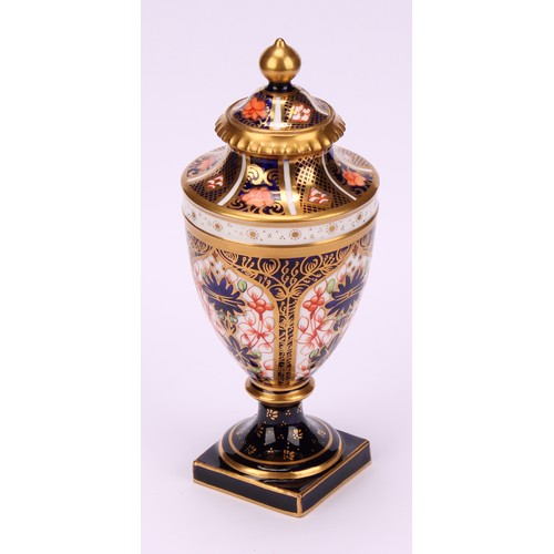 194 - A near pair of Royal Crown Derby 1128 Imari pattern ovoid pedestal vases, domed covers, gilt finials... 