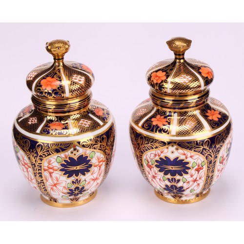 243 - An associated pair of Royal Crown Derby 1128 Imari pattern ovoid vases, each with crown shaped cover... 