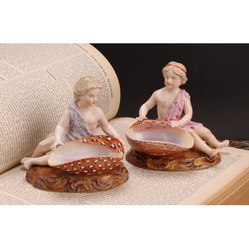 282 - A pair of 19th century Sitzendorf figural table salts, of children holding seashells, decorated in p... 