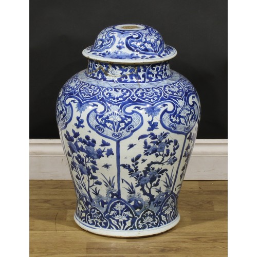 320 - A Chinese baluster temple jar and cover, decorated in tones of underglaze blue with panels of flower... 