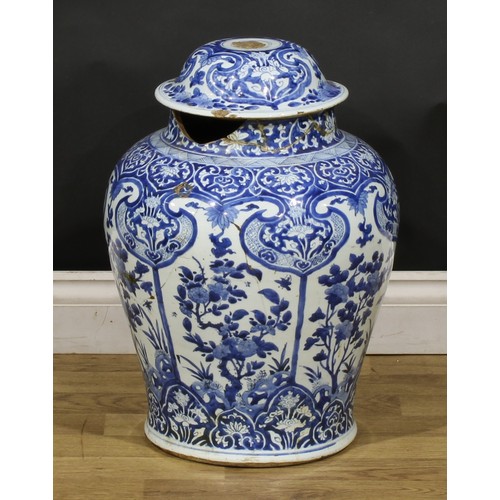 320 - A Chinese baluster temple jar and cover, decorated in tones of underglaze blue with panels of flower... 