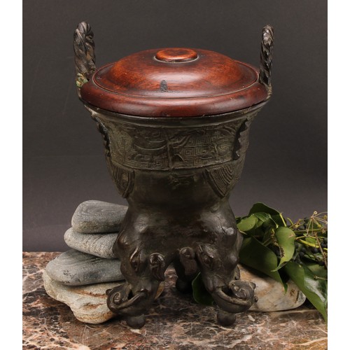 337 - A Chinese patinated bronze ding censer, cast in the archaic manner, twist handles, outswept rim, ele... 