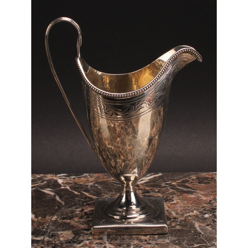 813 - A George III silver helmet shaped cream jug, bright-cut engraved and outlined with wrigglework, bead... 