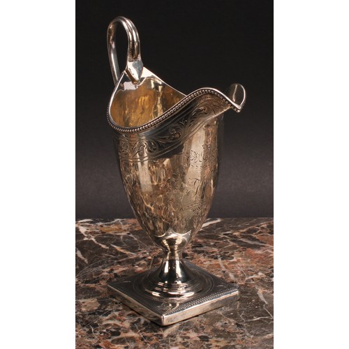 813 - A George III silver helmet shaped cream jug, bright-cut engraved and outlined with wrigglework, bead... 