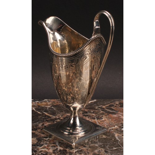 813 - A George III silver helmet shaped cream jug, bright-cut engraved and outlined with wrigglework, bead... 