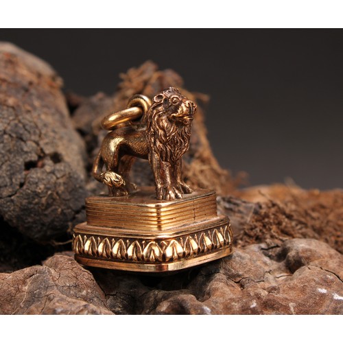 1253 - A 19th century gold coloured metal fob seal, surmounted with a lion, lotus border, the citrine matri... 