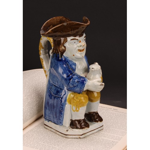 110 - An early 19th century Prattware Toby jug, seated holding a jug of foaming ale, painted in polychrome... 