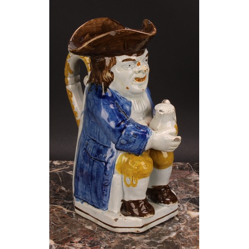 110 - An early 19th century Prattware Toby jug, seated holding a jug of foaming ale, painted in polychrome... 