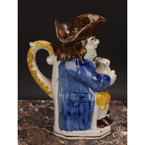 110 - An early 19th century Prattware Toby jug, seated holding a jug of foaming ale, painted in polychrome... 