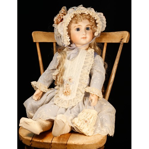 7111 - A reproduction bisque head doll, the bisque head inset with fixed blue glass eyes, painted features ... 