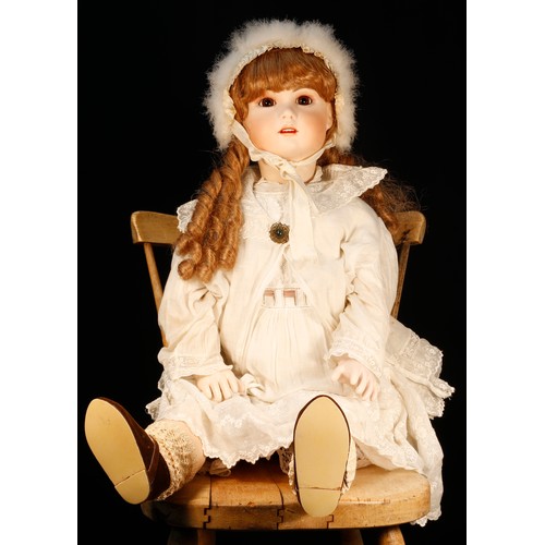 7113 - A reproduction bisque head doll, the bisque head inset with fixed brown glass eyes, painted features... 