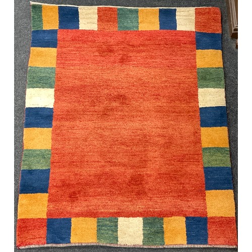 168 - A contemporary designed multitone russet rug, green, blue, yellow cube banded border, 189cm x 143cm;... 