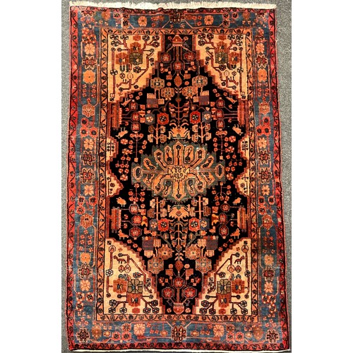 205 - A Persian Navahand rug / carpet, hand-knotted with oval-shaped medallion, within a field of stylised... 