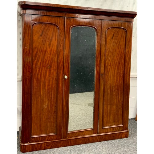 216 - A Victorian mahogany compactum triple wardrobe, serpentine-shaped cornice, above two arch-paneled do... 