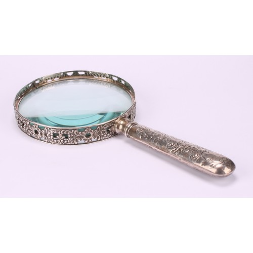 36 - A Victorian silver magnifying glass, the bezel pierced and cast with flowering foliate scrolls, the ... 