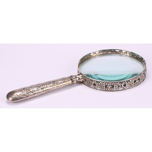 36 - A Victorian silver magnifying glass, the bezel pierced and cast with flowering foliate scrolls, the ... 