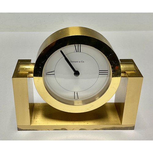 484 - A Tiffany & Co brass clock, white circular dial with Roman numerals to quarters, rotating on a frame... 