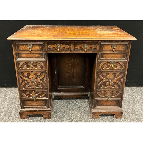 106 - A Jacobean Revival oak kneehole desk, carved with strap work, 73cm high, 92cm wide, 50cm deep, c.193... 