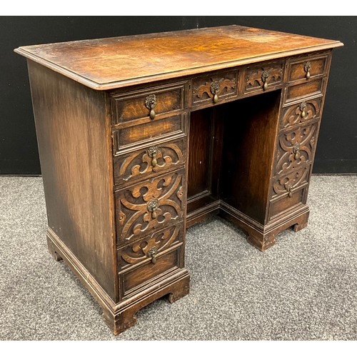 106 - A Jacobean Revival oak kneehole desk, carved with strap work, 73cm high, 92cm wide, 50cm deep, c.193... 