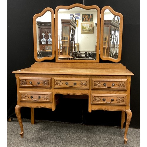 121 - A French Provincial style oak dressing table, serpentine shaped triple mirror, above a base with fiv... 