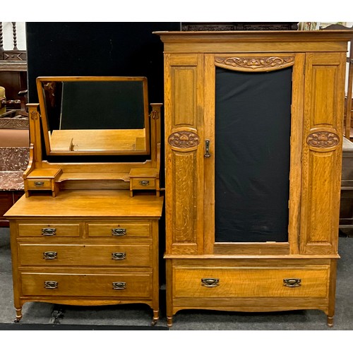 151 - An early 20th century Arts and Crafts style oak wardrobe and dressing table, with Art Nouveau carved... 