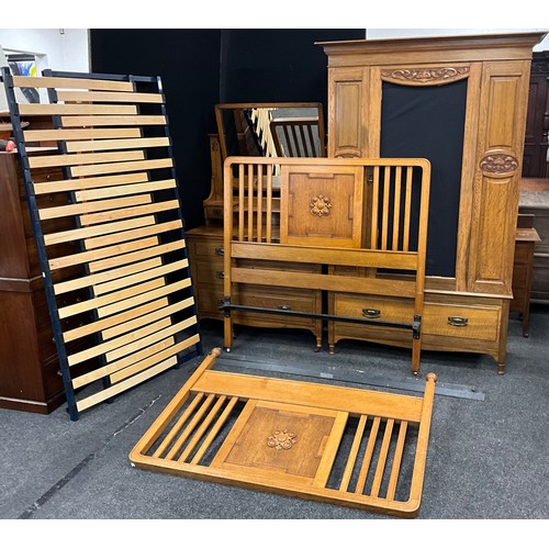 151 - An early 20th century Arts and Crafts style oak wardrobe and dressing table, with Art Nouveau carved... 