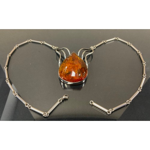 296 - A silver and copal amber necklace, pear copal ridged cabochon, unmarked silver coloured metal mounts... 