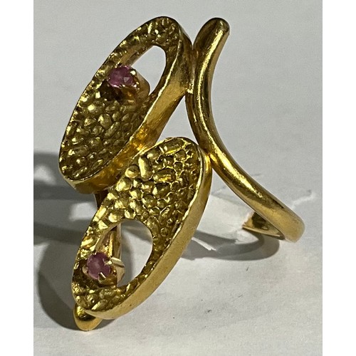 162 - An 18ct gold modernist design crossover ring, as pair of stylised textured flowerheads, each set wit... 