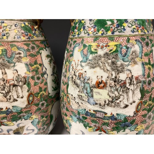 423 - A pair of 19th century Chinese Canton famille Rose vases, decorated with traditional figure panels, ... 