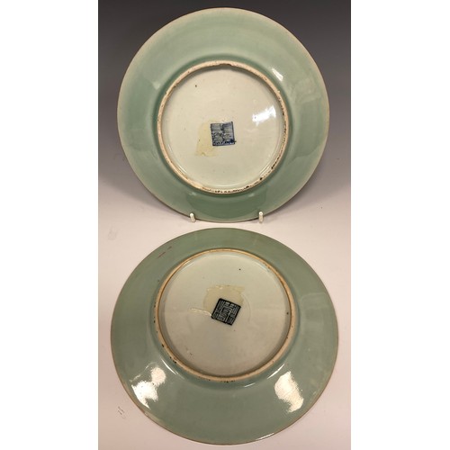 424 - A pair of Chinese Famille Rose celadon plates, decorated with traditional motifs of instruments, wea... 