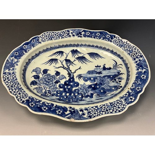 432 - An 18th century Chinese blue and white serving dish of shaped oval form, the deep bowl decorated wit... 